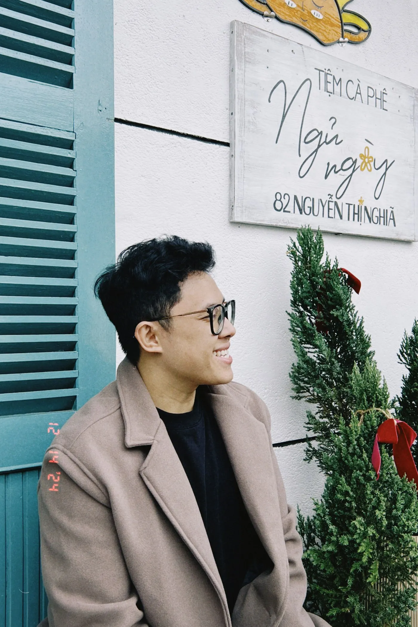 Dinh Huy Nguyen smiling outside a café, in a camel coat